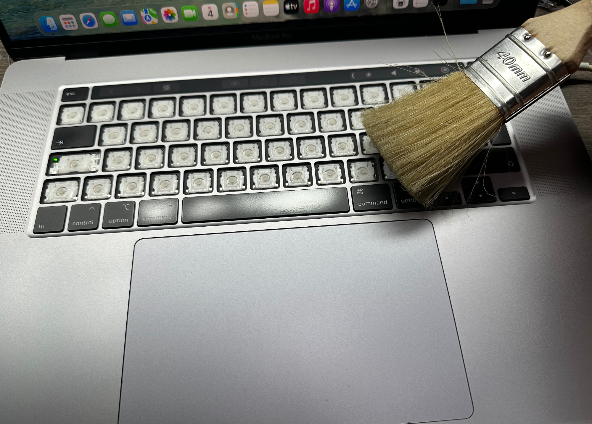 MacBook toetsenbord wordt gereinigd met een kwast nadat de toetsen zijn verwijderd