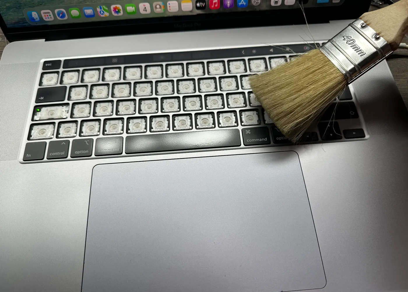 MacBook toetsenbord wordt gereinigd met een kwast nadat de toetsen zijn verwijderd